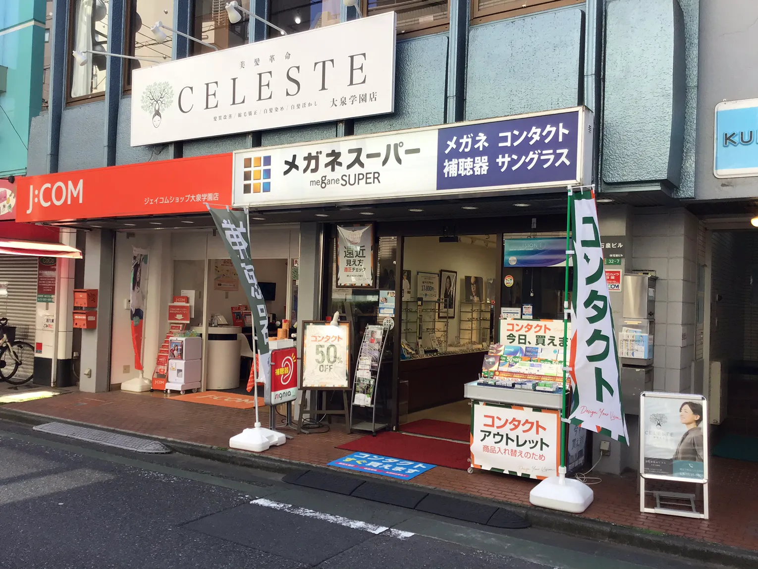 メガネスーパー大泉学園店の外観、ビルの1階 白と青の欄間看板